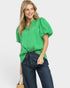 Woman wearing a green blouse and blue jeans on a plain background