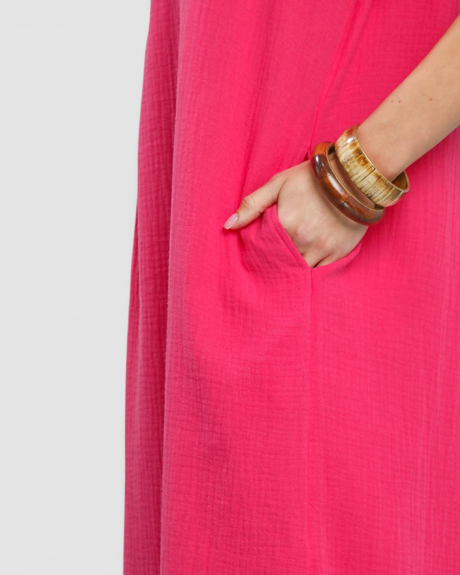 Person wearing a bright pink dress with a plain background