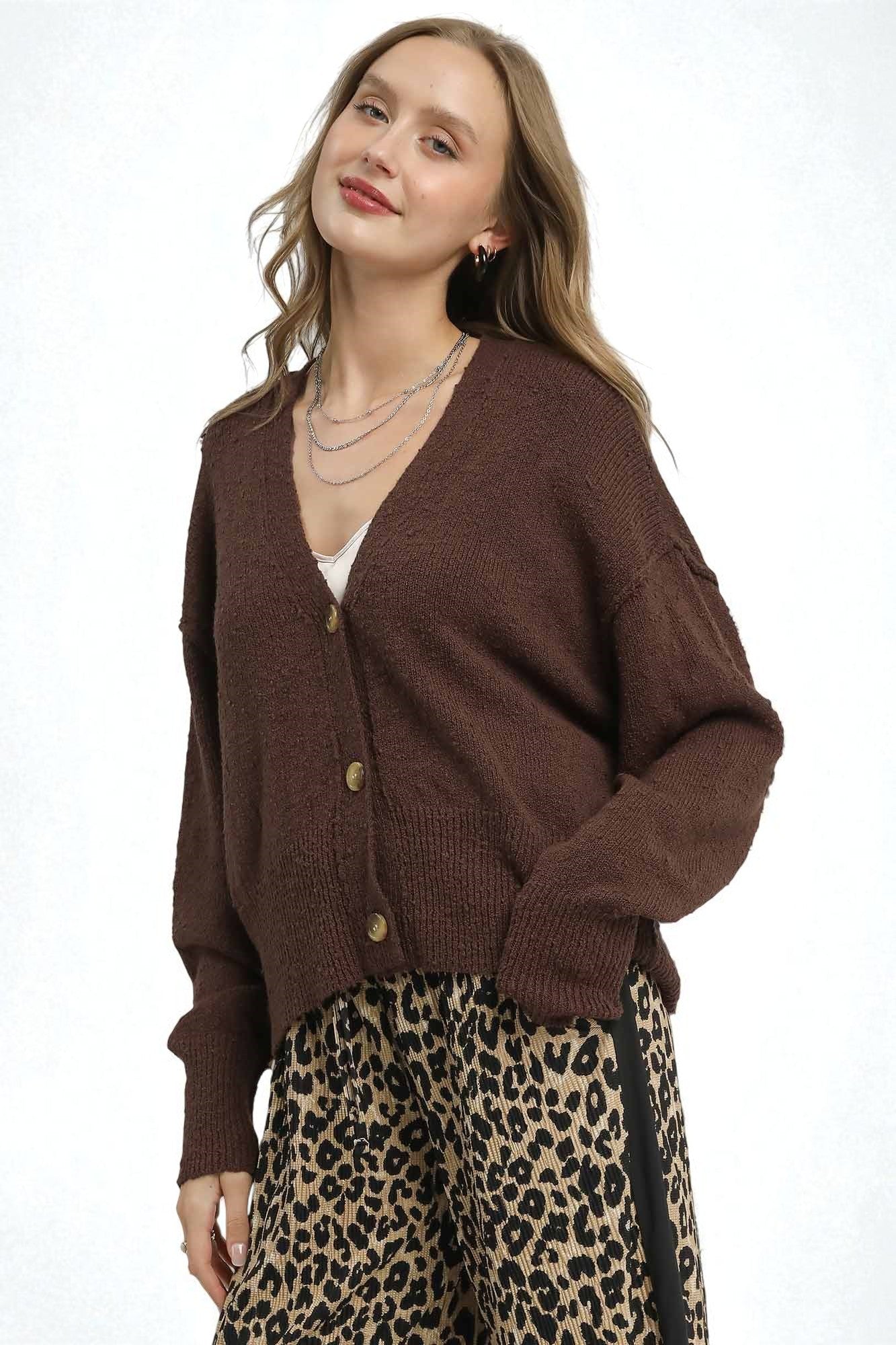 Woman wearing a brown cardigan and leopard print pants on a white background