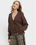 Woman wearing a brown cardigan and leopard print pants on a white background