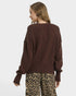 Person wearing a brown sweater and leopard print pants on a white background