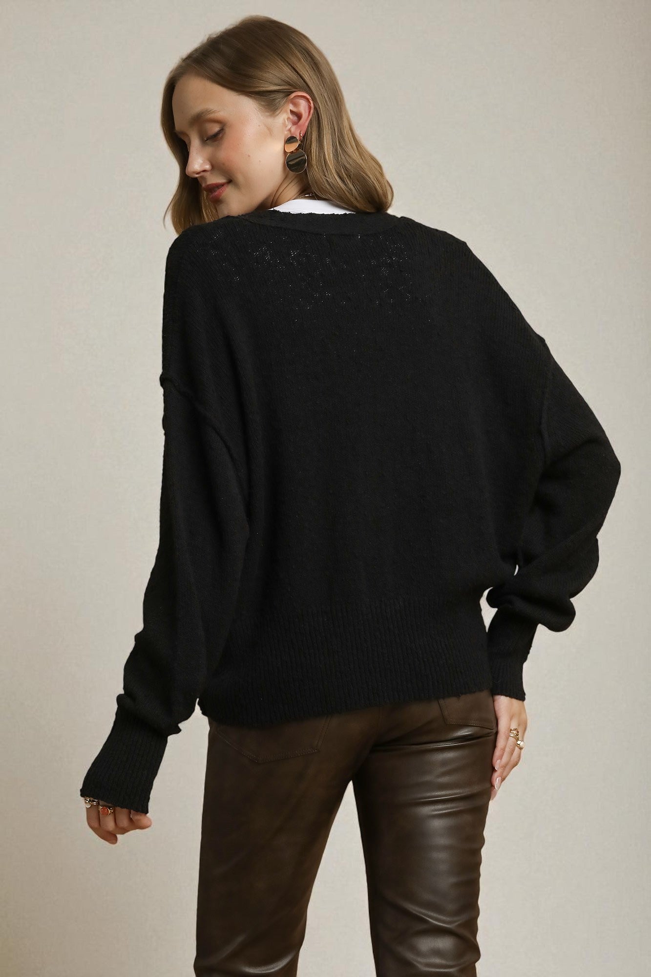Person wearing a black sweater and brown pants on a plain background