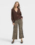 Woman wearing a brown cardigan and leopard print pants on a white background