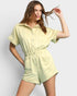 Woman wearing a light green romper against a plain background