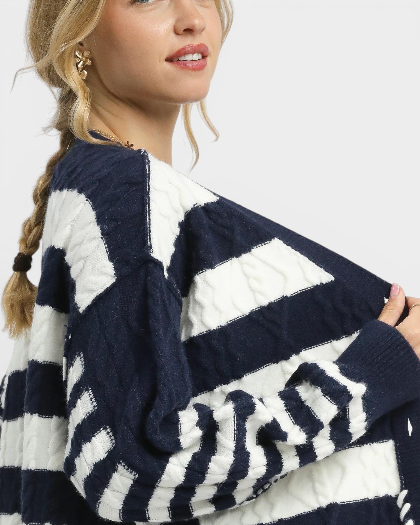 Woman wearing a navy and white striped sweater on a plain background