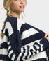 Woman wearing a navy and white striped sweater on a plain background