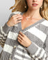 Woman wearing a gray and white striped cardigan with a neutral background