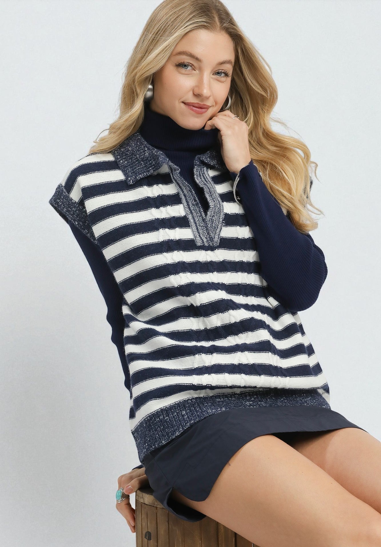 Woman wearing a navy and white striped sweater vest on a white background