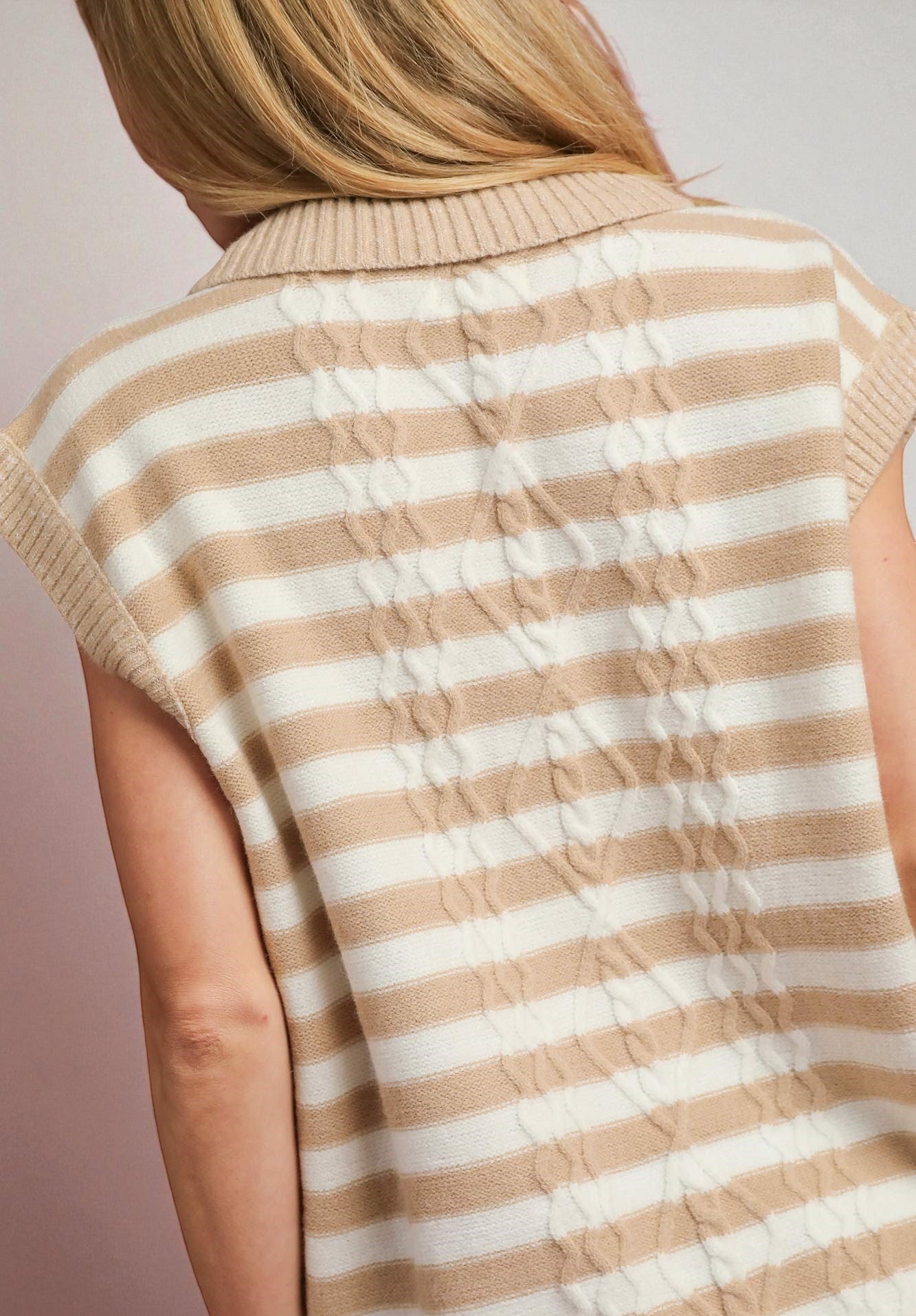 Beige and white striped sleeveless sweater vest on a plain background