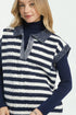 Woman wearing a navy and white striped vest over a dark blue long-sleeve shirt on a white background