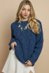 Woman wearing a blue sweater and white skirt against a pink background