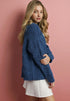 Woman wearing a blue sweater and white skirt against a pink background