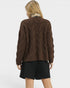 Person wearing a brown cable knit sweater on a white background