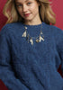 Woman wearing a blue sweater with a decorative necklace against a red background