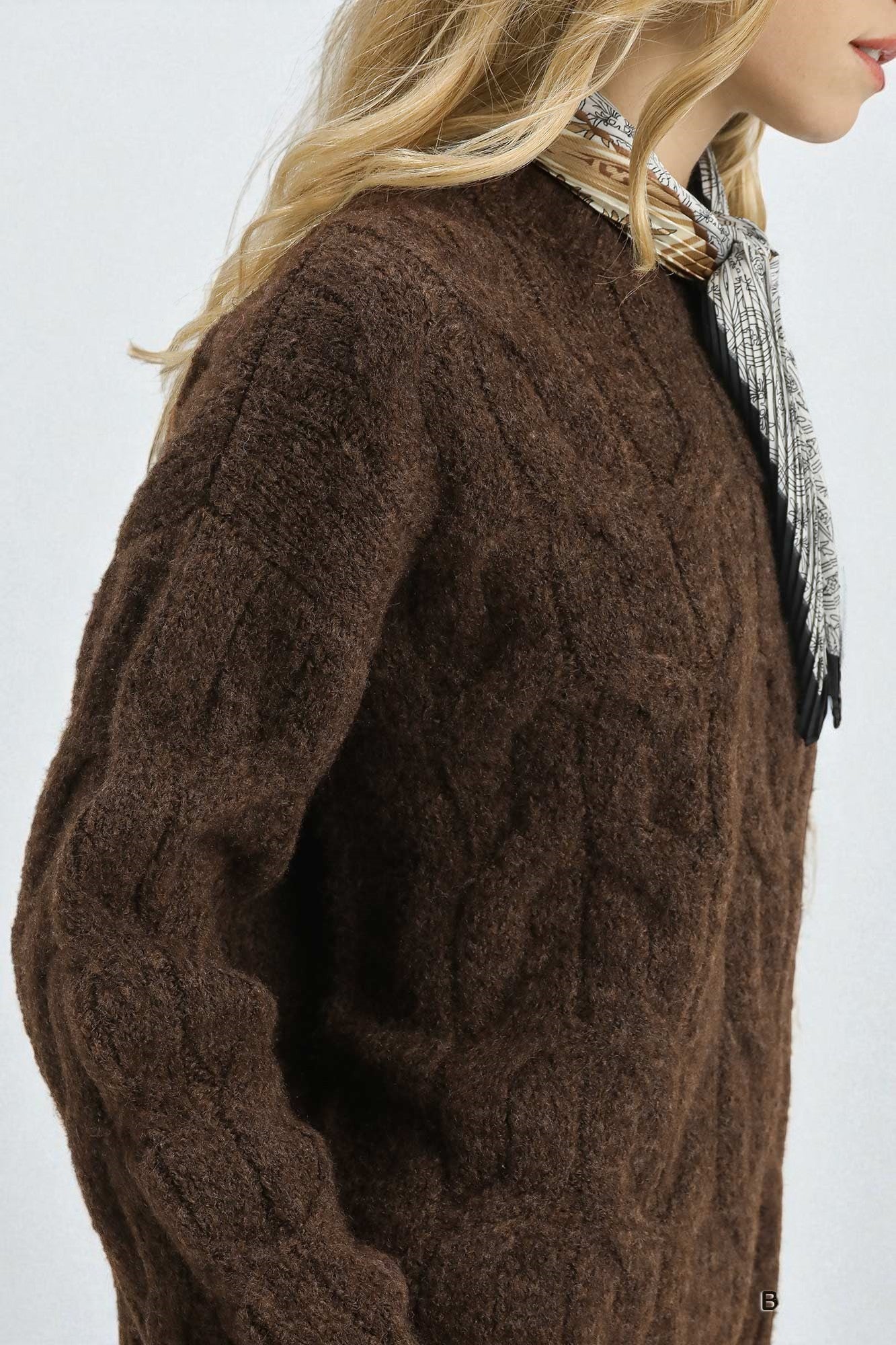 Brown cable knit sweater worn by a person with a white background