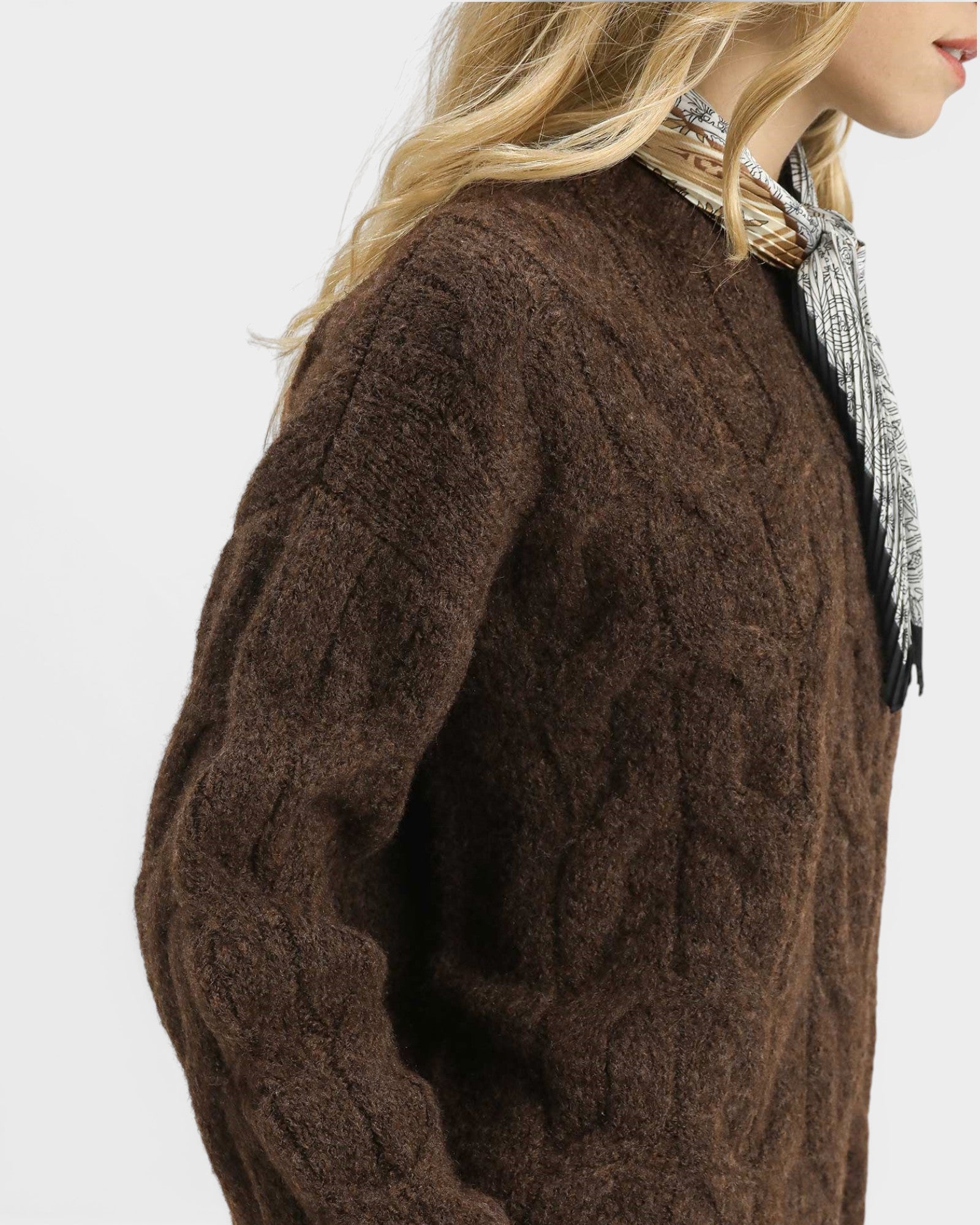 Brown cable knit sweater worn by a person on a white background