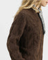 Brown cable knit sweater worn by a person on a white background