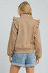 Person wearing a brown jacket with ruffled shoulders on a plain background