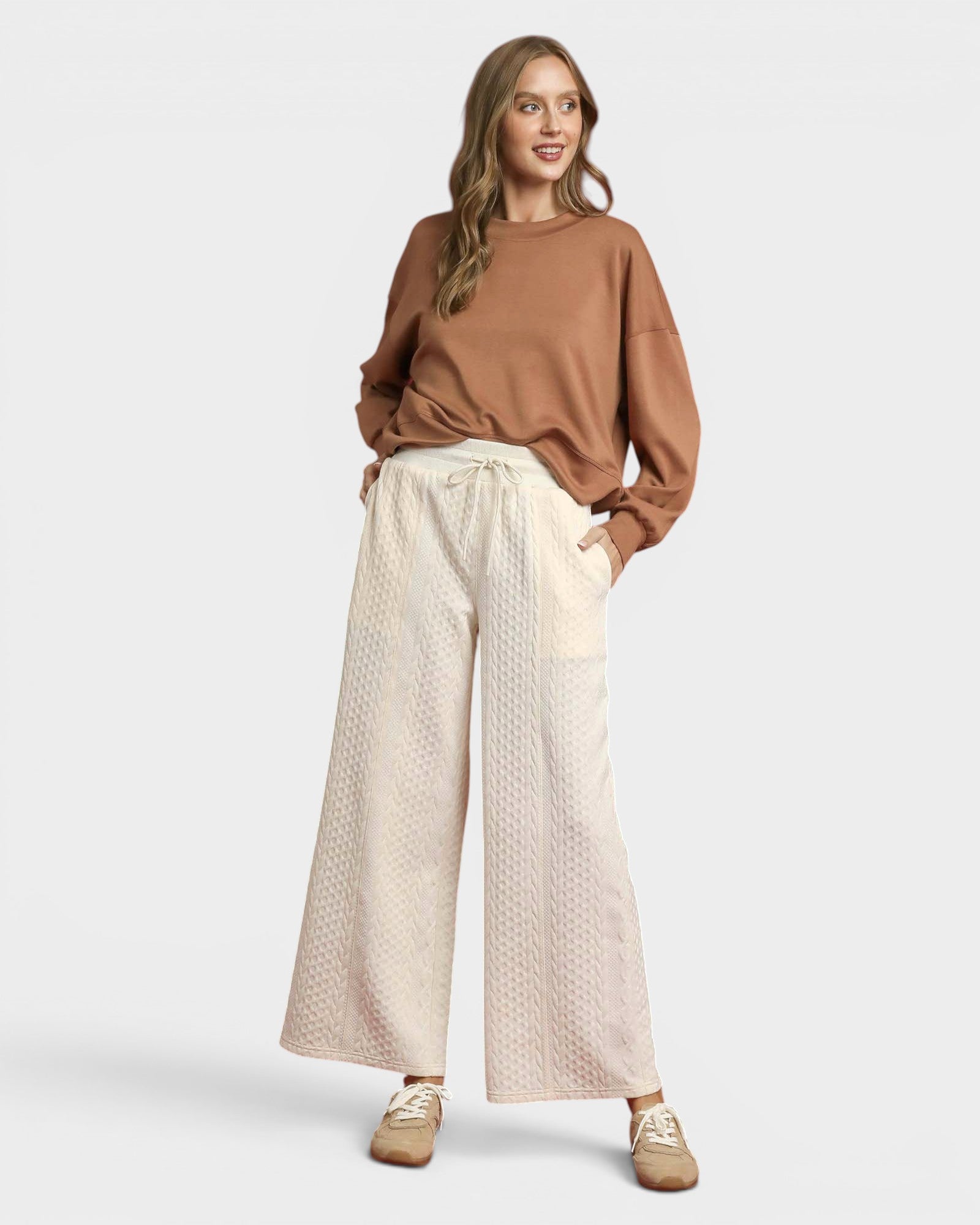 Woman wearing a brown top and beige wide-leg pants on a white background