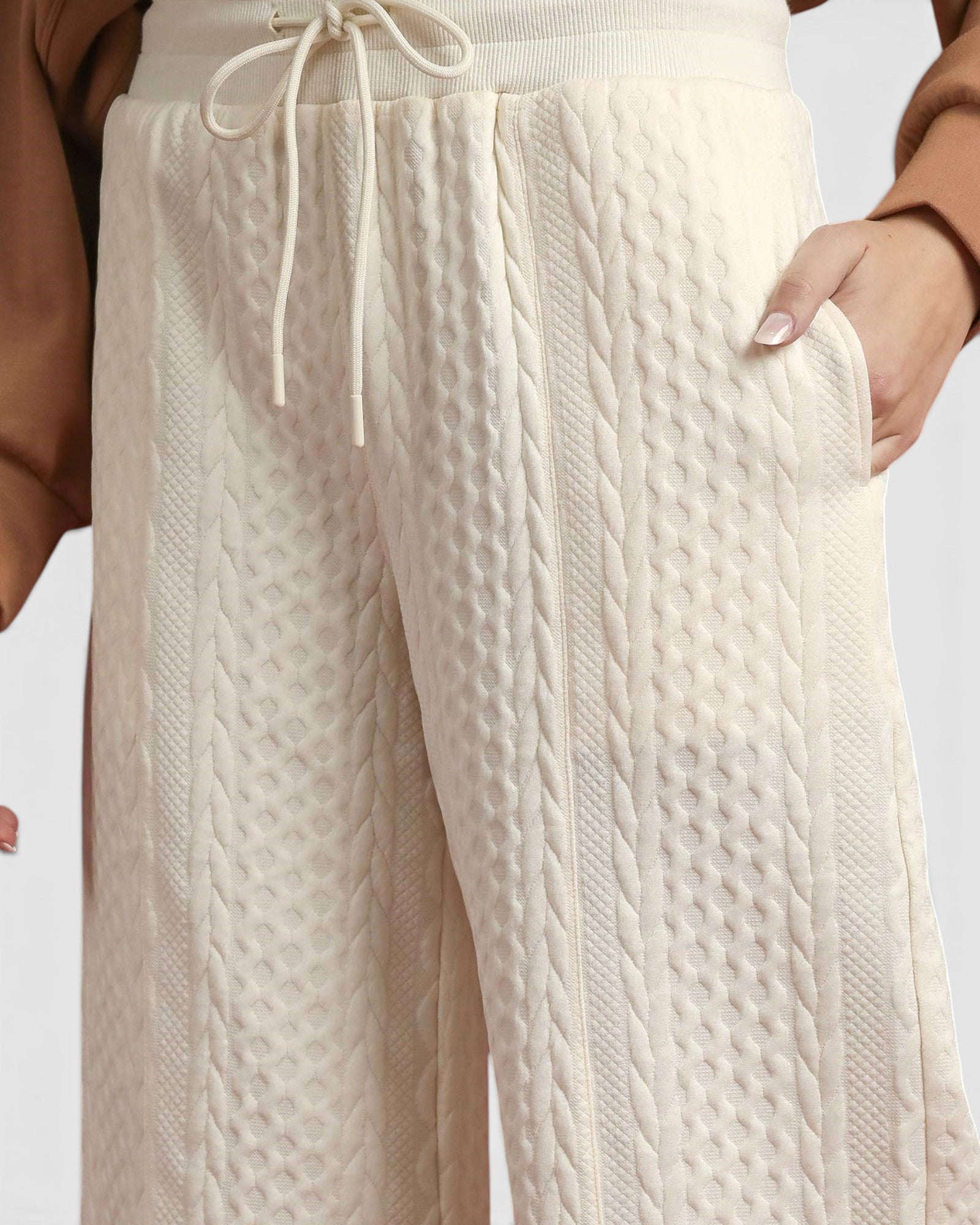 Close-up of cream-colored cable knit pants with a blurred background
