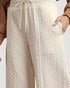Close-up of cream-colored cable knit pants with a blurred background