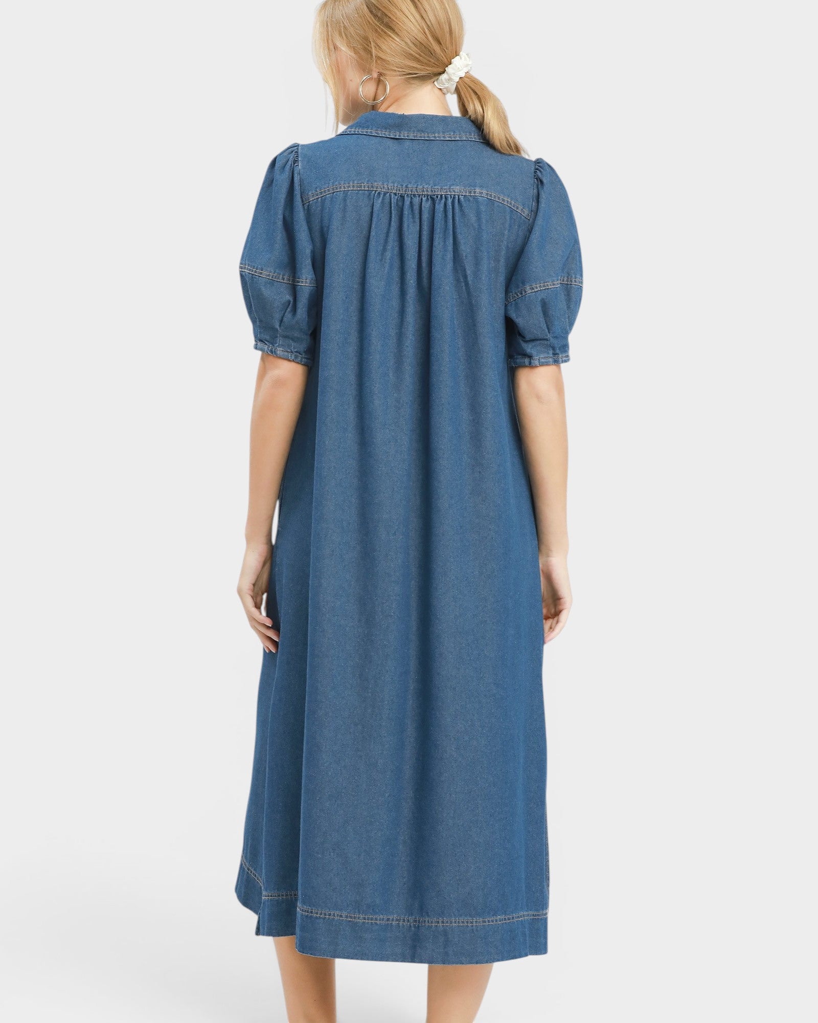 Blue denim dress worn by a person on a white background