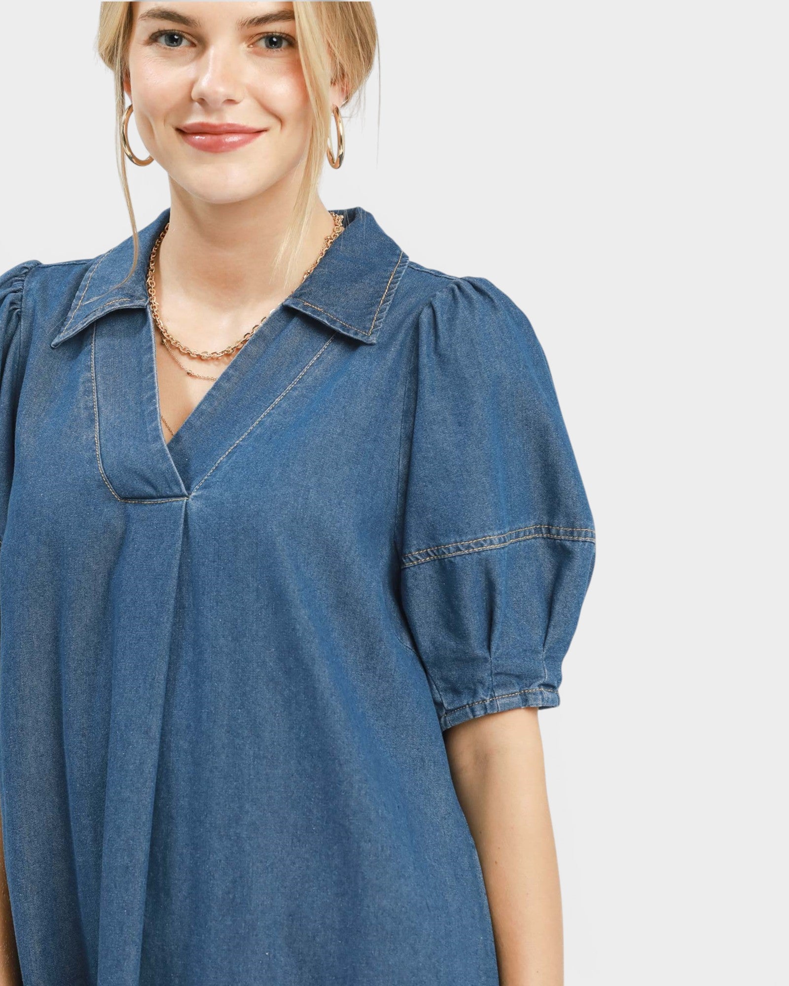 Woman wearing a blue denim dress on a plain background