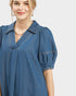 Woman wearing a blue denim dress on a plain background