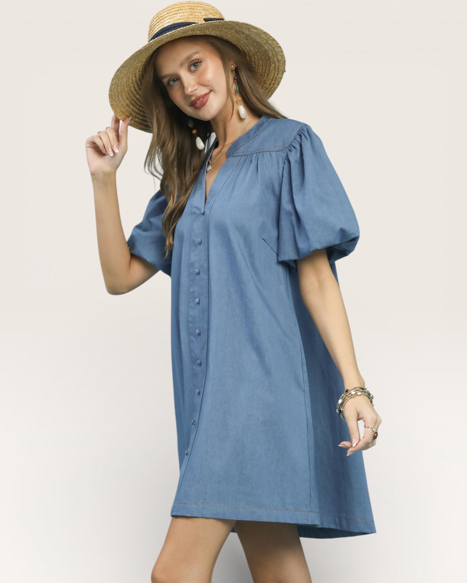 Woman wearing a blue dress and straw hat on a plain background