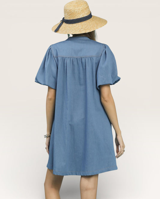 Woman wearing a blue dress and straw hat on a plain background