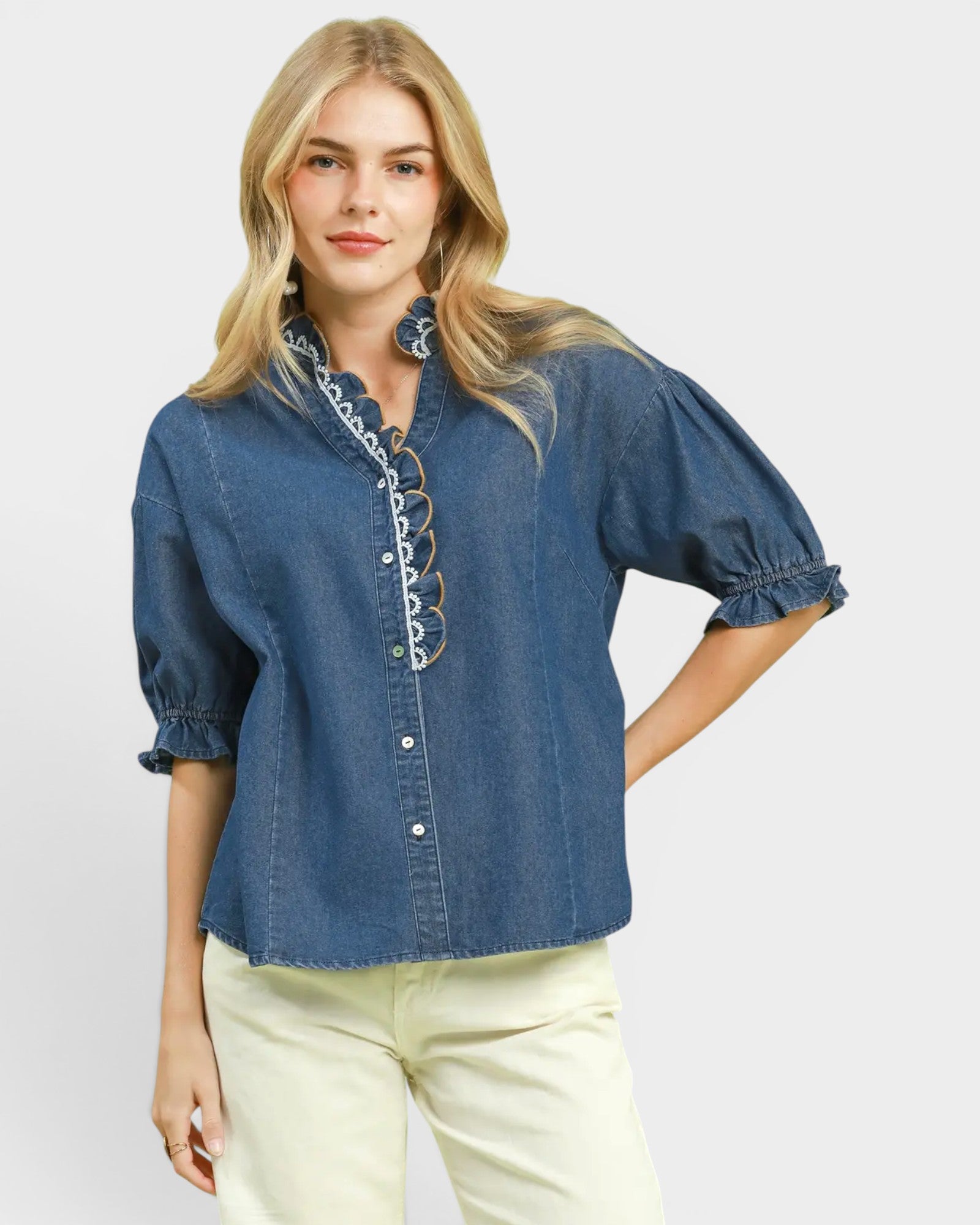 Woman wearing a blue denim blouse with ruffled details on a white background