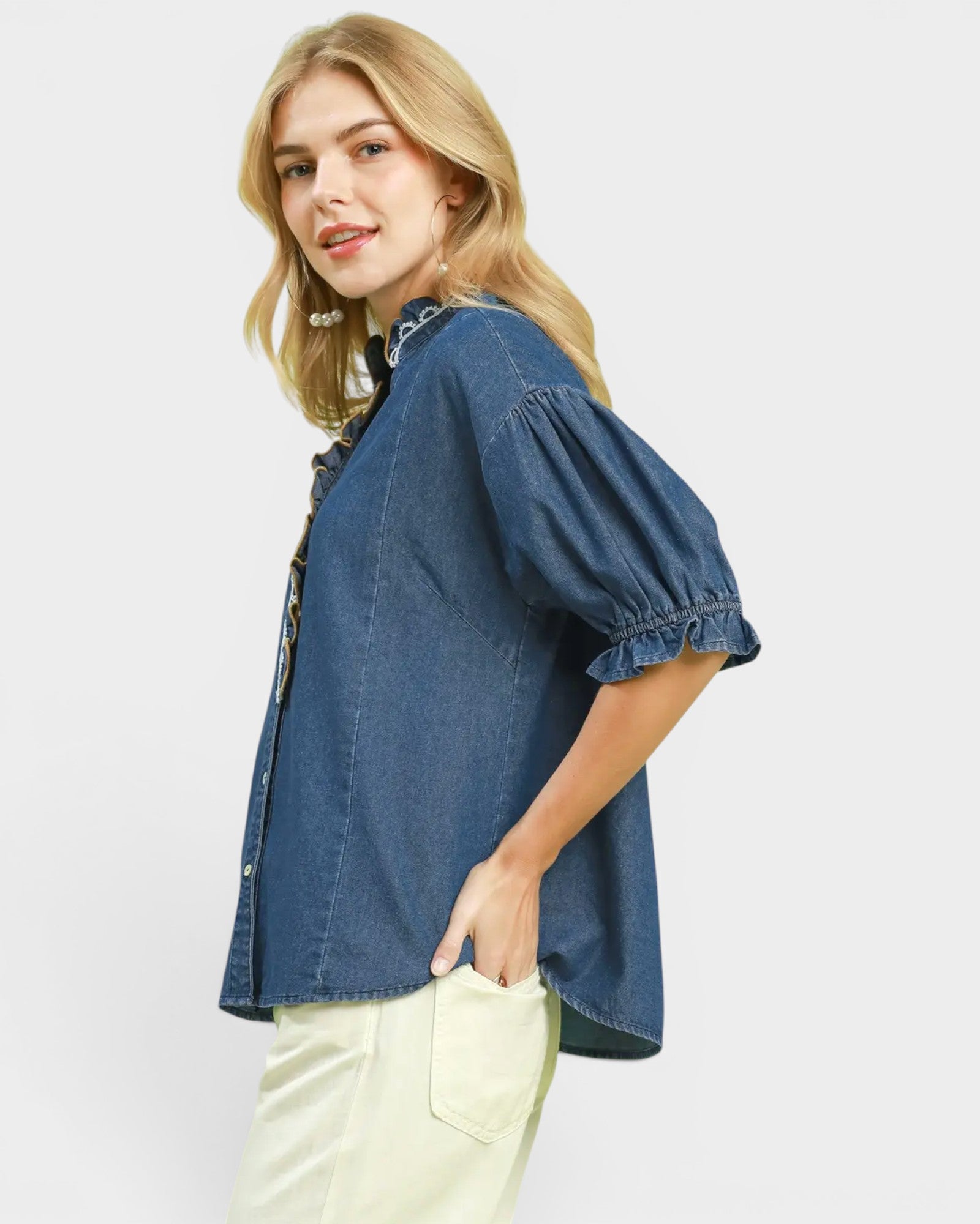 Woman wearing a blue denim shirt with puffed sleeves on a white background