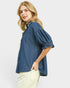 Woman wearing a blue denim shirt with puffed sleeves on a white background