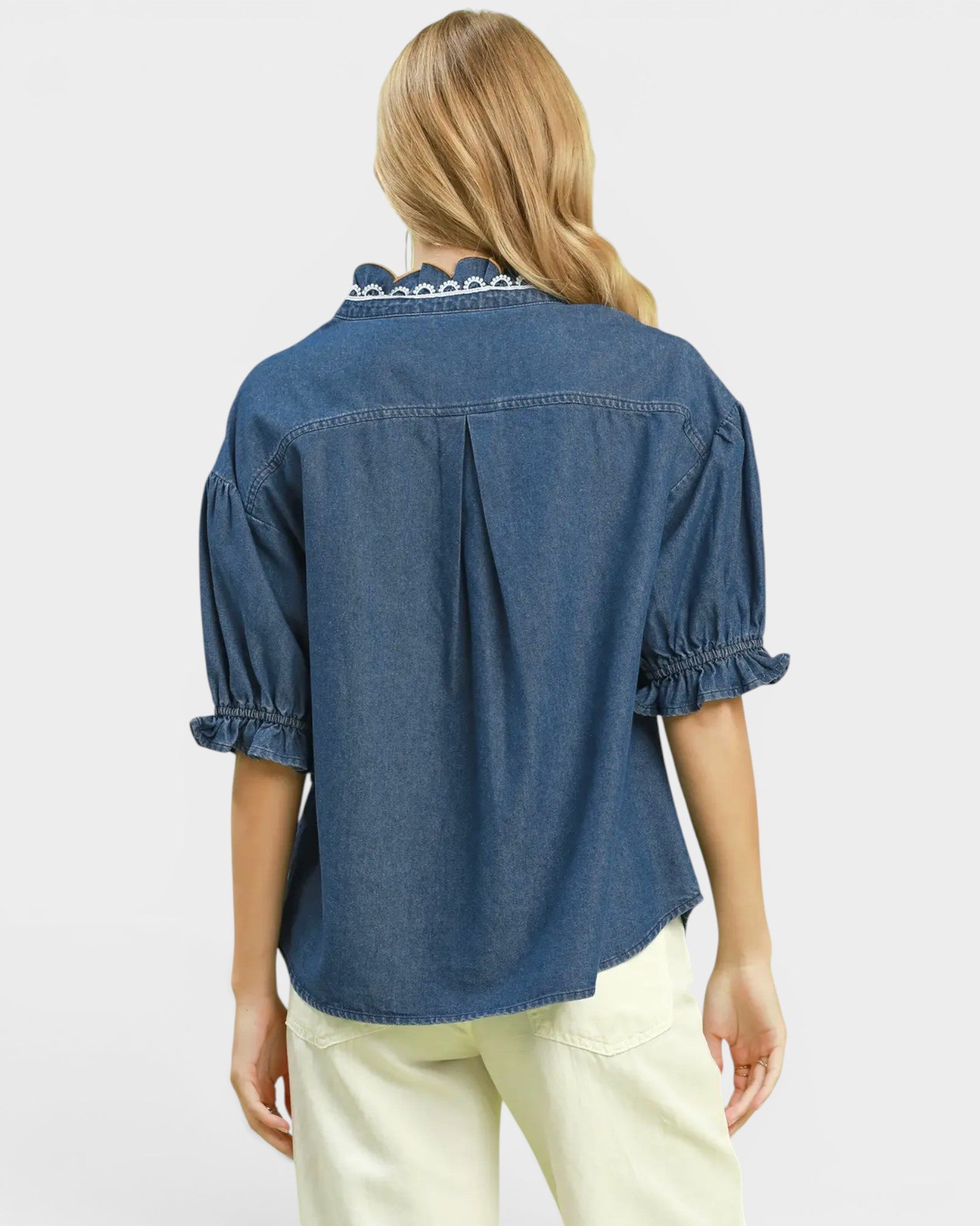 Woman wearing a blue denim shirt with white trim on a light gray background