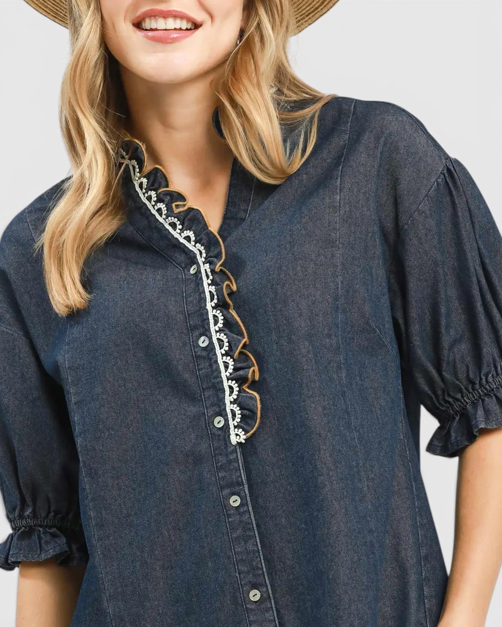 Woman wearing a blue denim dress with lace details on a plain background