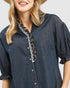 Woman wearing a blue denim dress with lace details on a plain background