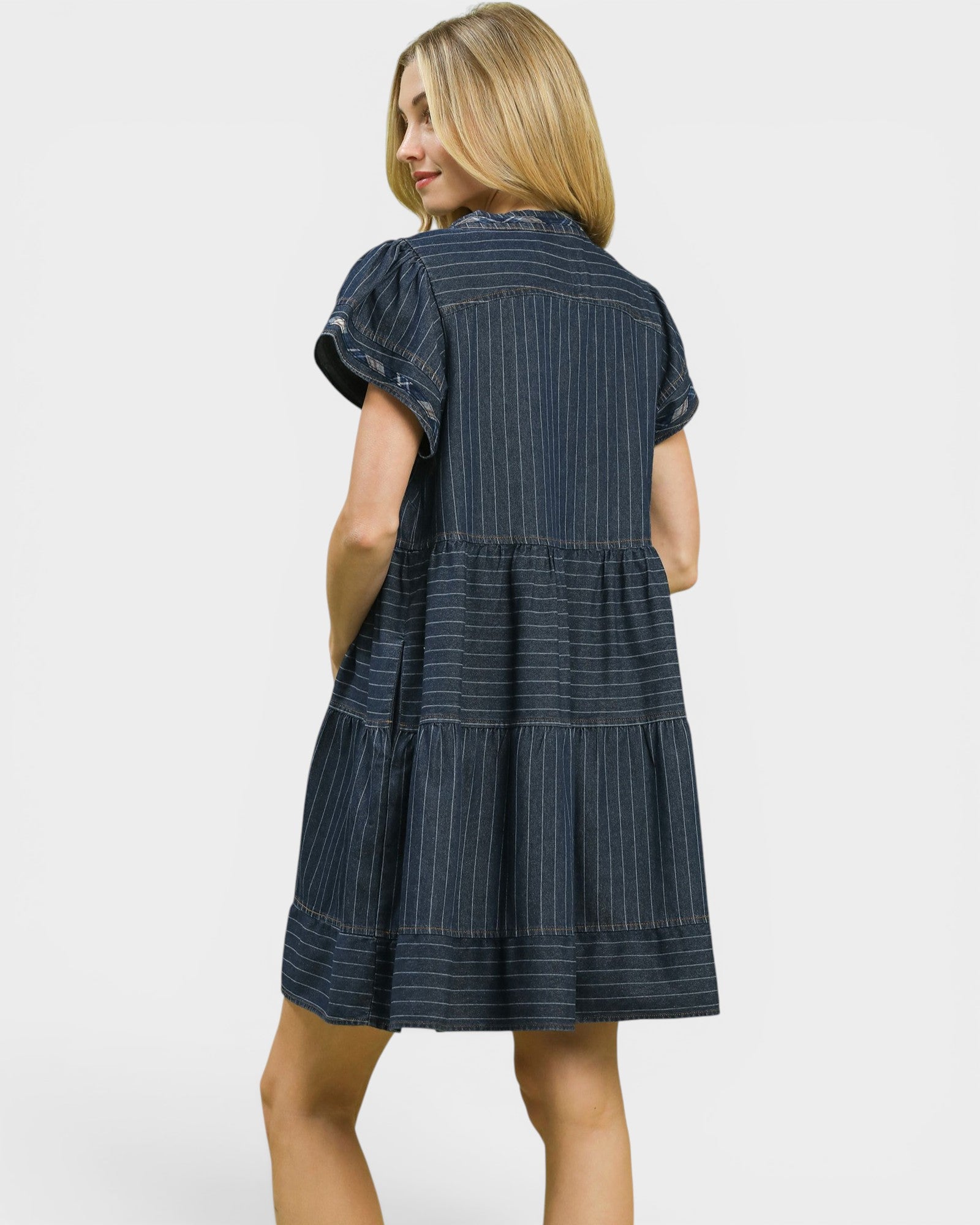 Woman wearing a blue tiered dress on a white background