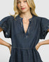 Woman wearing a blue pinstripe dress with a plain background