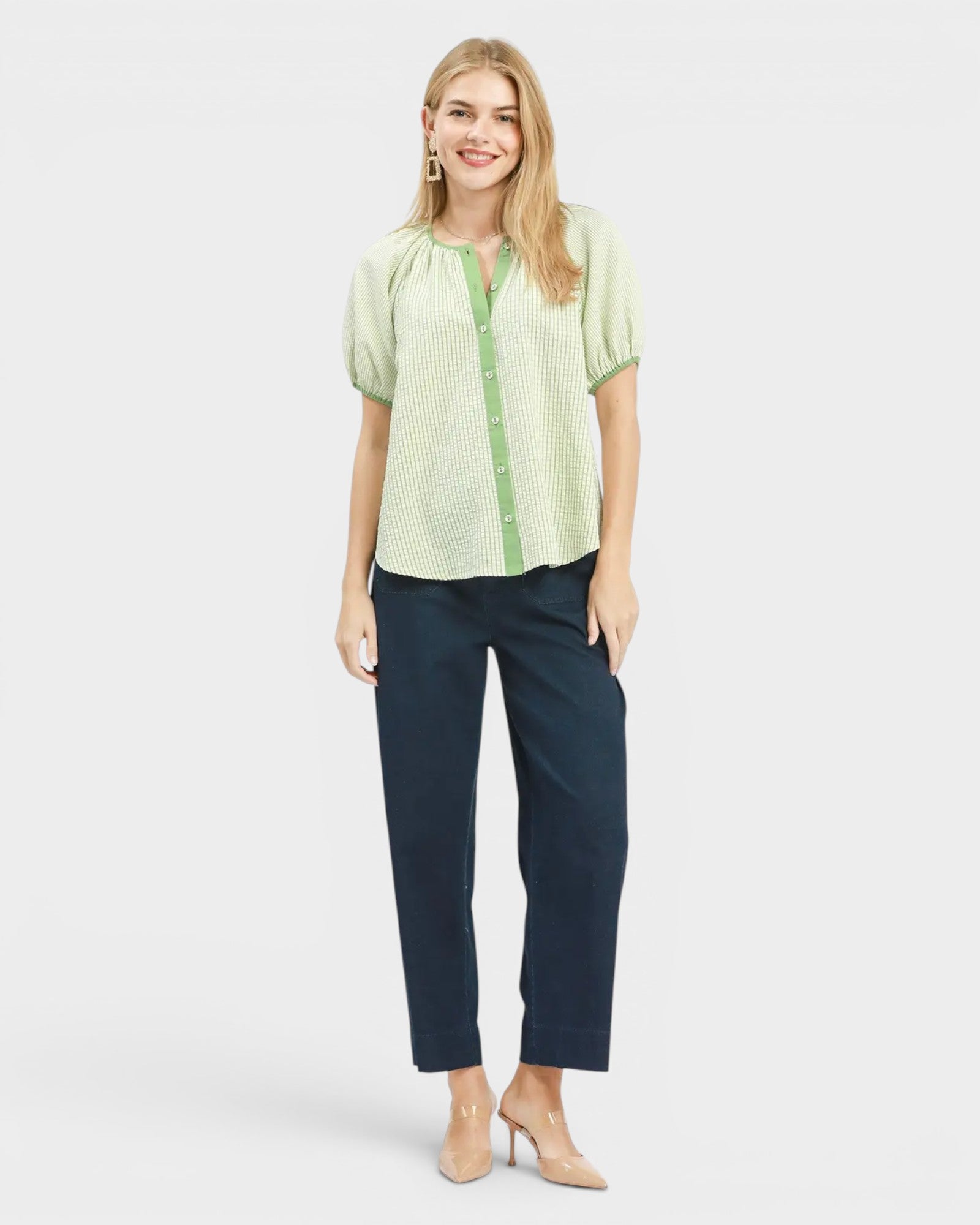 Woman wearing a green checkered blouse and navy pants on a white background
