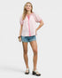 Woman wearing a pink and white patterned shirt with denim shorts on a white background