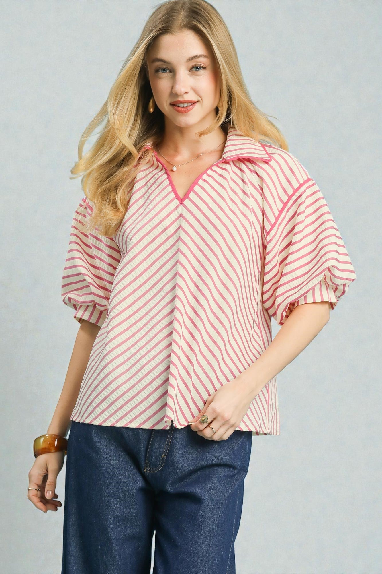 Woman wearing a red and white striped shirt with blue jeans on a gray background