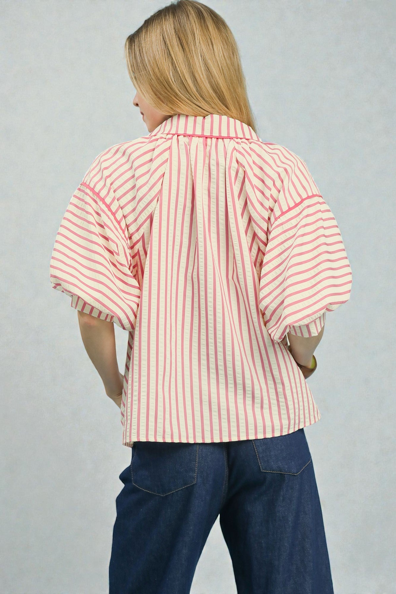 Person wearing a red and white striped shirt with blue pants on a gray background