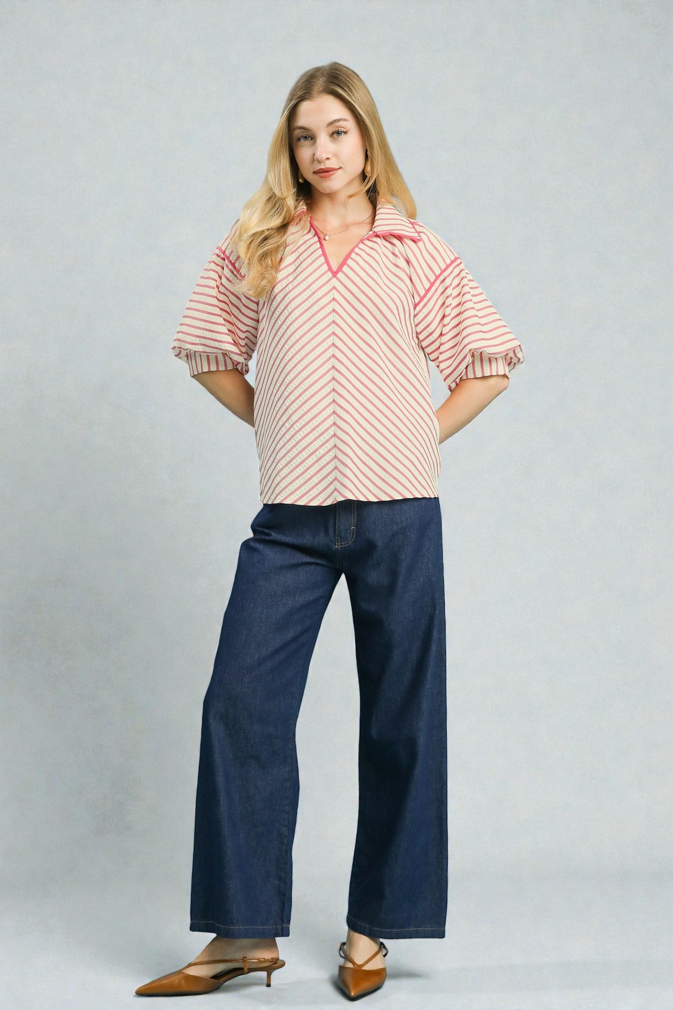 Woman wearing a striped shirt and blue jeans on a plain background