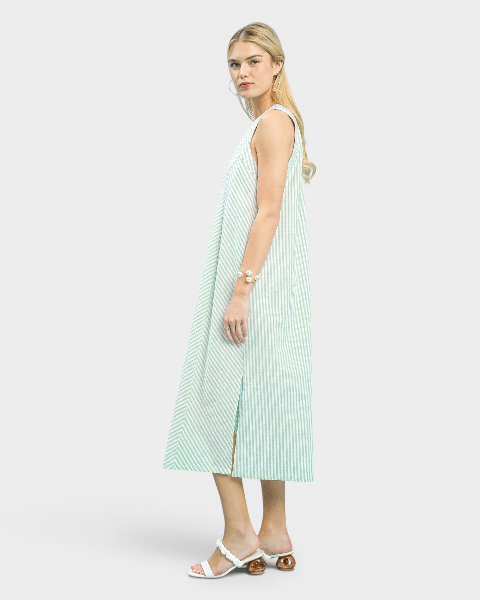 Woman wearing a light green and white striped dress on a white background