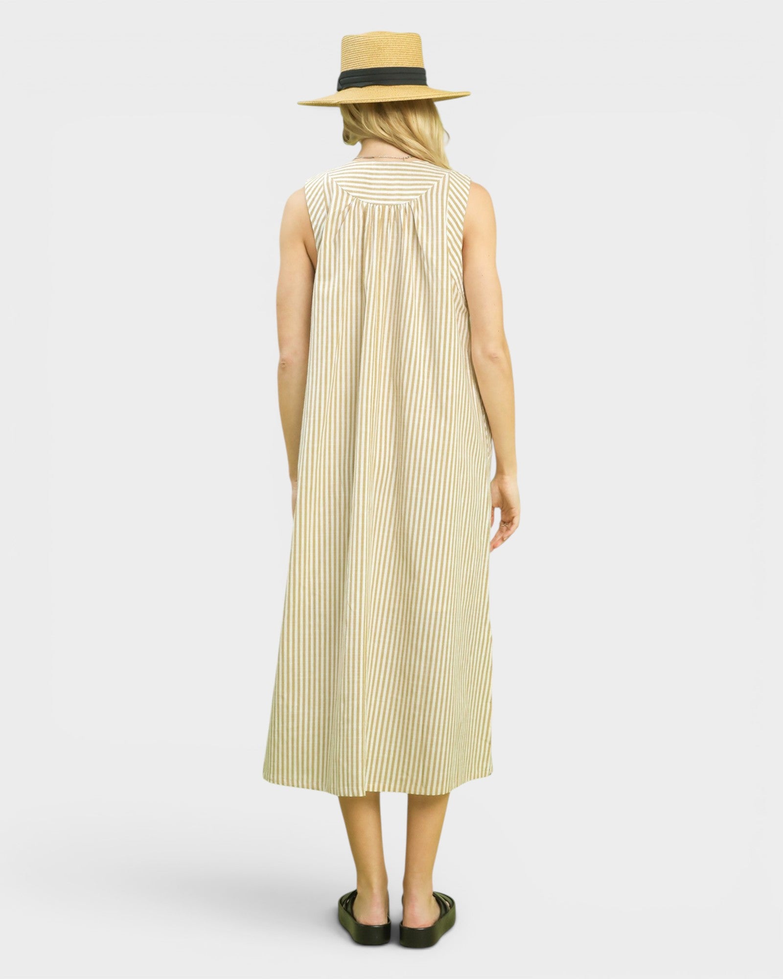 Woman wearing a brown striped dress and straw hat on a white background