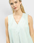 Woman wearing a light green and white striped sleeveless top against a plain background