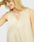 Woman wearing a beige and white striped sleeveless dress against a plain background