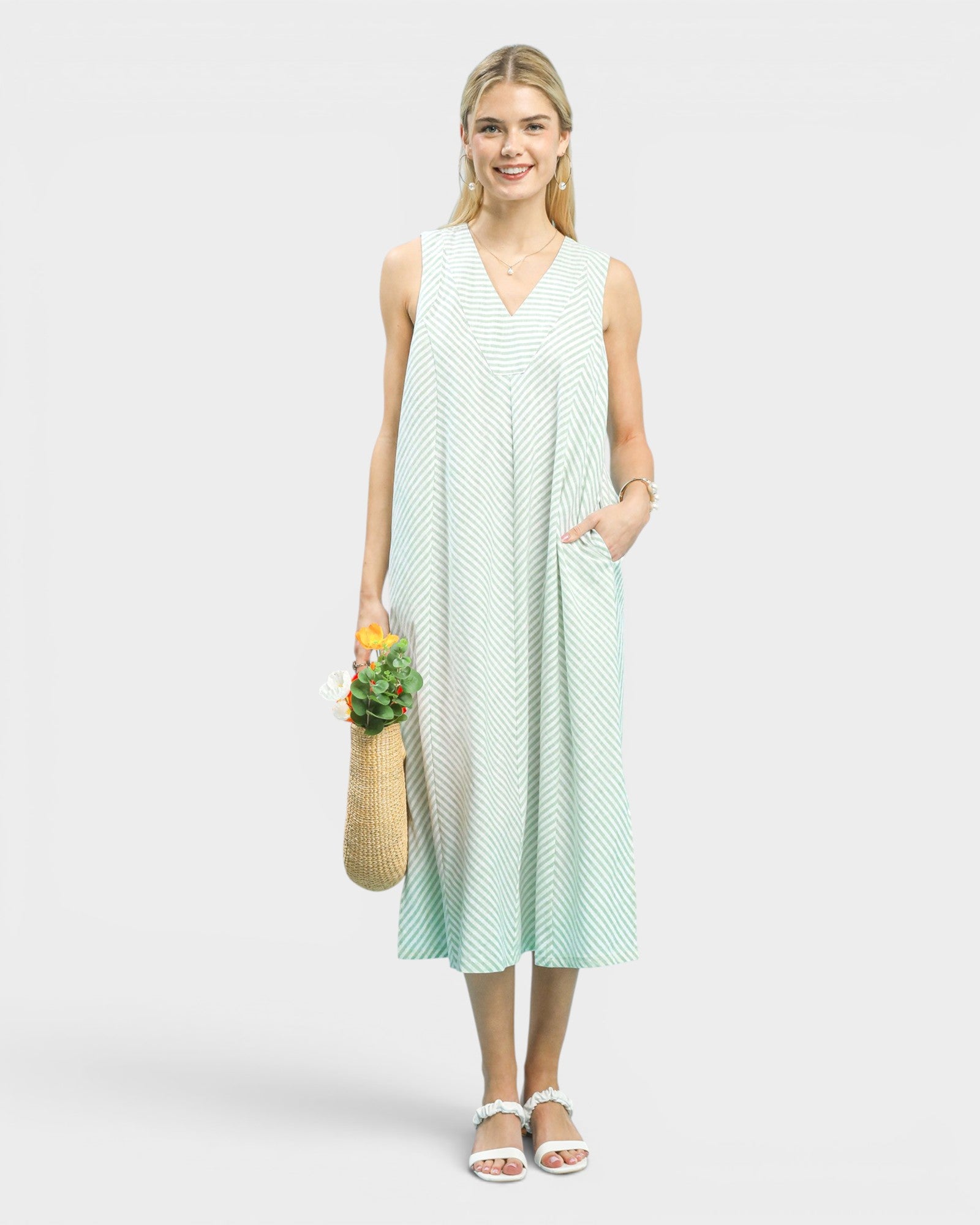 Woman wearing a light green sleeveless dress with a white background