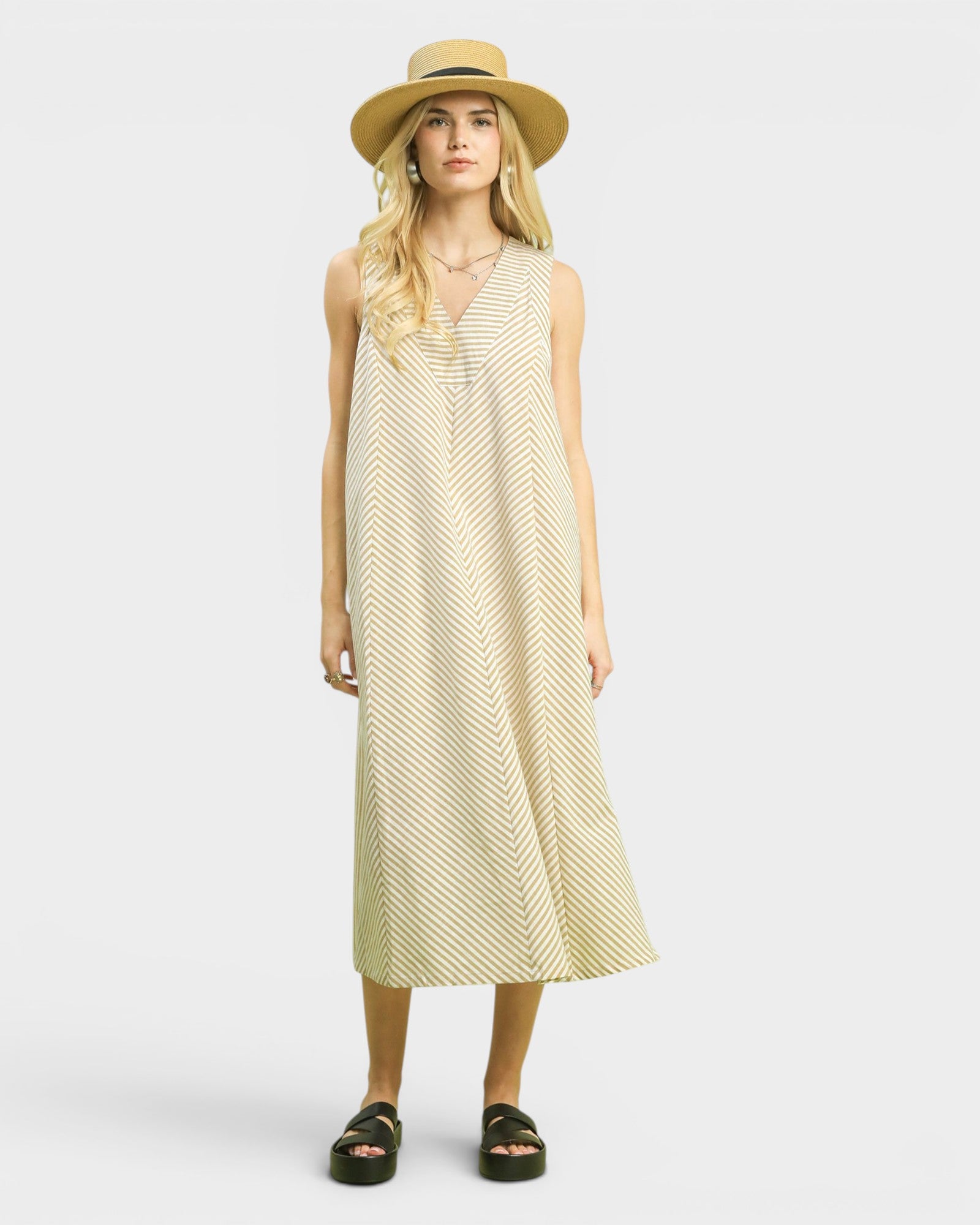 Woman wearing a brown striped dress and straw hat on a white background
