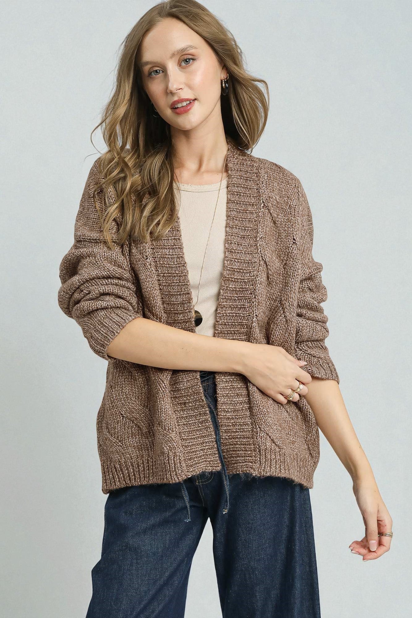 Woman wearing a brown knitted cardigan on a plain background